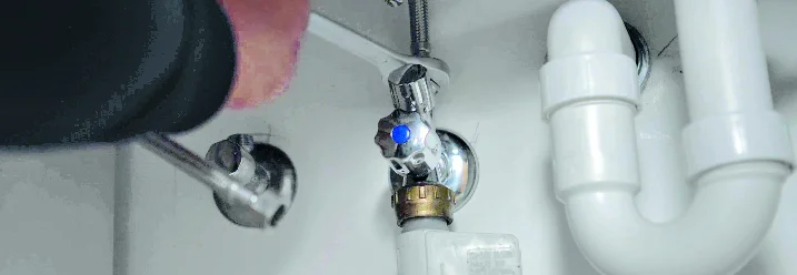 Person montiert Wasserhahn mit Schraubenschlüssel.